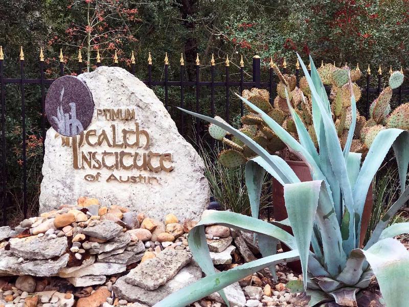 A sign marks the entrance to Optimum Health Institute Austin, home to holistic retreats - spiritual, emotional, and physical.