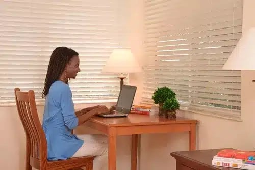 A woman completes her daily journaling exercise on her laptop after participating in holistic workshops and classes.