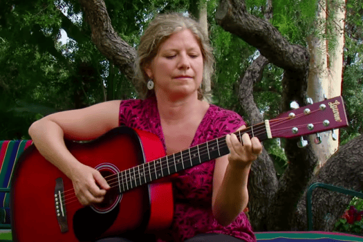 An OHI guest plays acoustic guitar for guests during a body and soul retreat at our holistic center